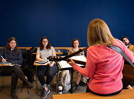 A woman teaching a guitar lesson to a group of people. Links to Gifts That Protect Your Assets
