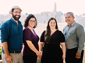 Four people smiling for a photo. Links to Gifts of Life Insurance