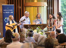 Photo of an event with a group singing and playing guitar to crowd. Links to Donor-Advised Funds